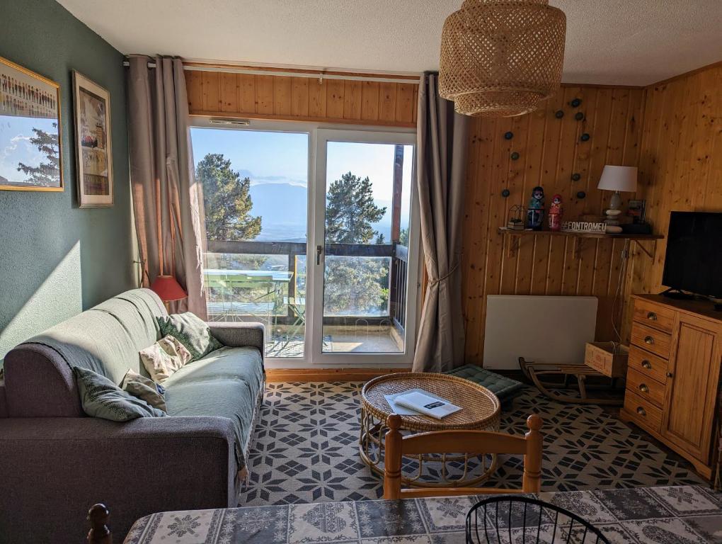 丰罗默奥代洛维亚Charmant appartement centre ville de Font-Romeu, vue montagne的带沙发和大窗户的客厅