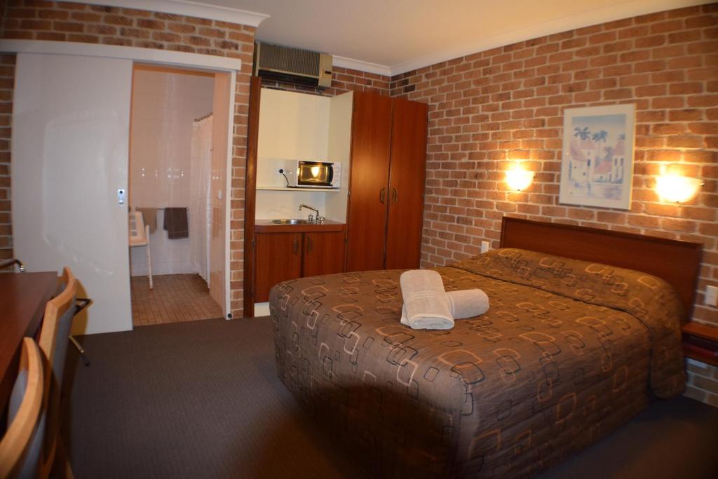 阿米代尔相思木汽车旅馆的一间卧室设有一张床和砖墙