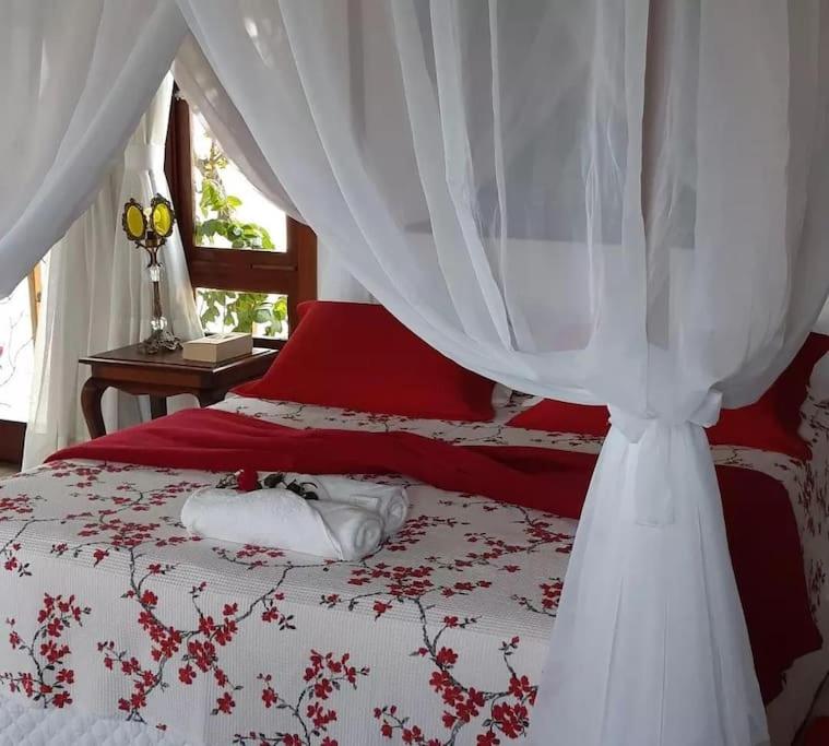 蒙蒂达斯加梅莱拉斯Chalé romântico, com vista panorâmica, para Casais的卧室配有红色和白色的床和天蓬