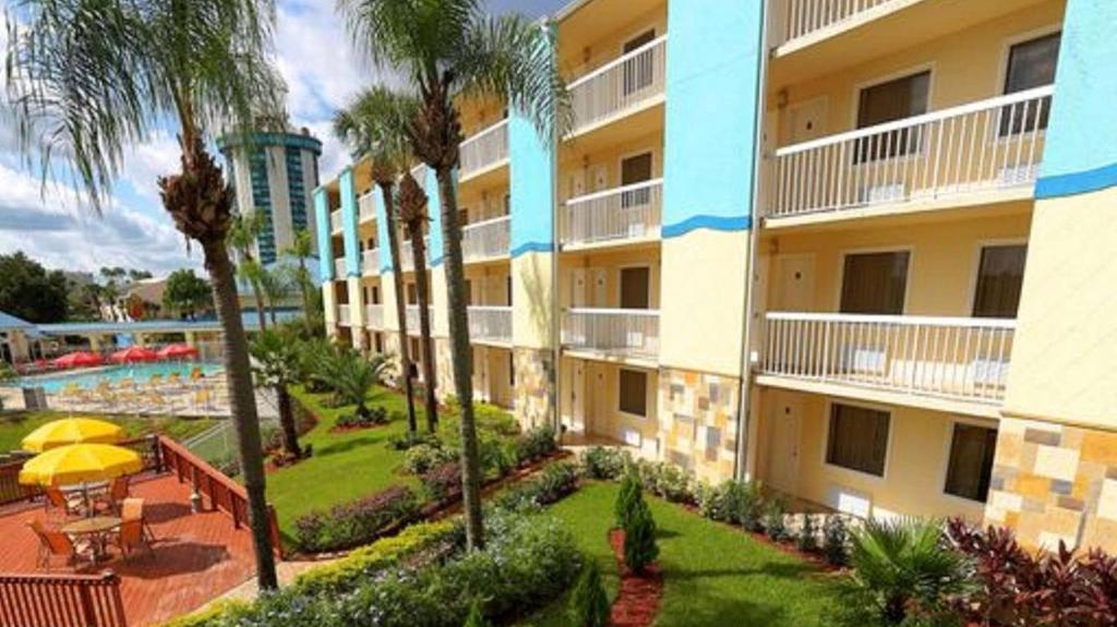 奥兰多Orlando International Drive North Hotel的公寓大楼设有游泳池和棕榈树