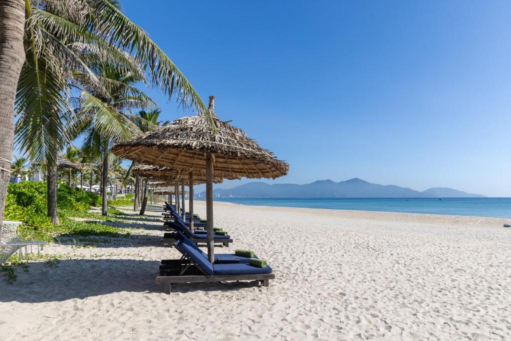 岘港Melia Danang Beach Resort的海滩上一排沙滩椅和遮阳伞