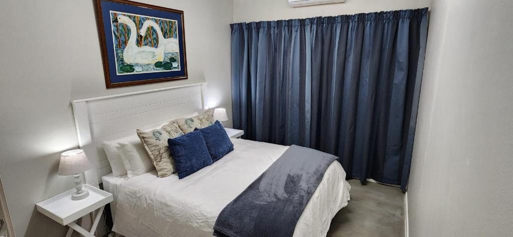 布隆方丹Cottage Rose的一间卧室配有一张带蓝色窗帘的大床