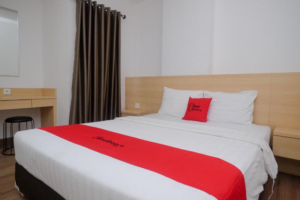 梭罗RedDoorz Apartment near Exit Toll Colomadu的一间卧室配有一张大床和红色枕头