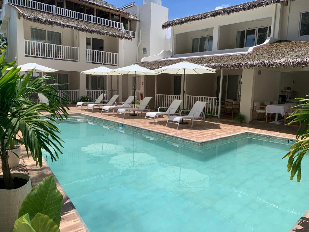 蓝海湾Le Clos des Bains Mauritius的酒店前的游泳池配有椅子和遮阳伞