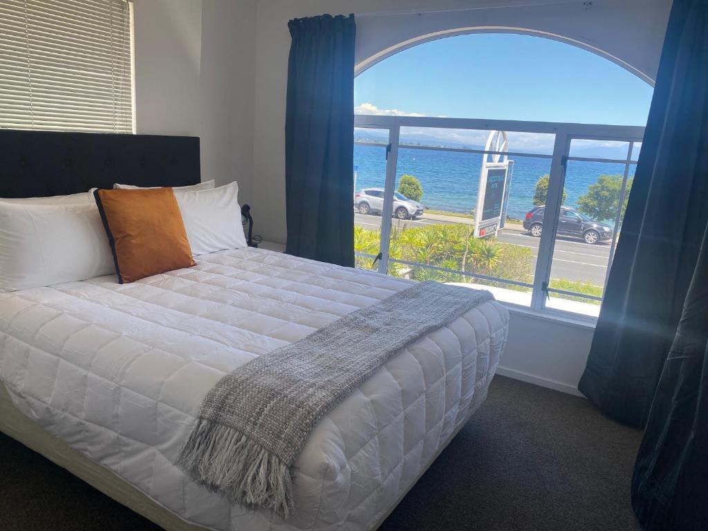 陶波Lakeside Taupo Motel的一间卧室设有一张床,享有海景