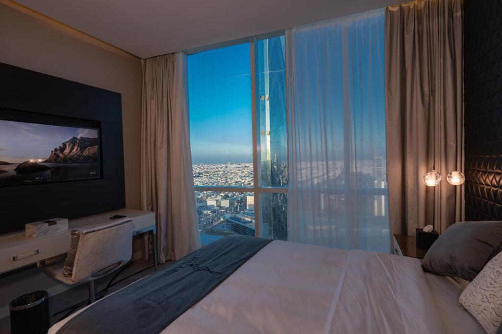 利雅德DAMAC Riyadh - Luxury Apartments的一间卧室配有一张床、一张书桌和一个大窗户