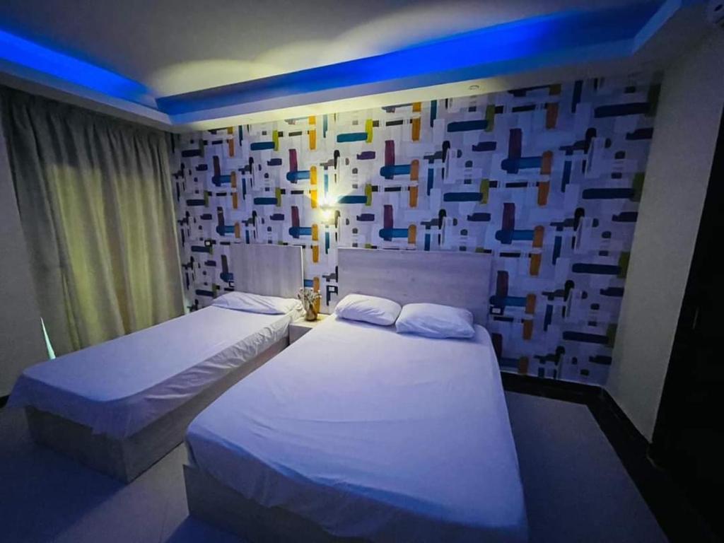 赫尔格达سيسيليا ريزورت的两张床位于带方形墙的客房内