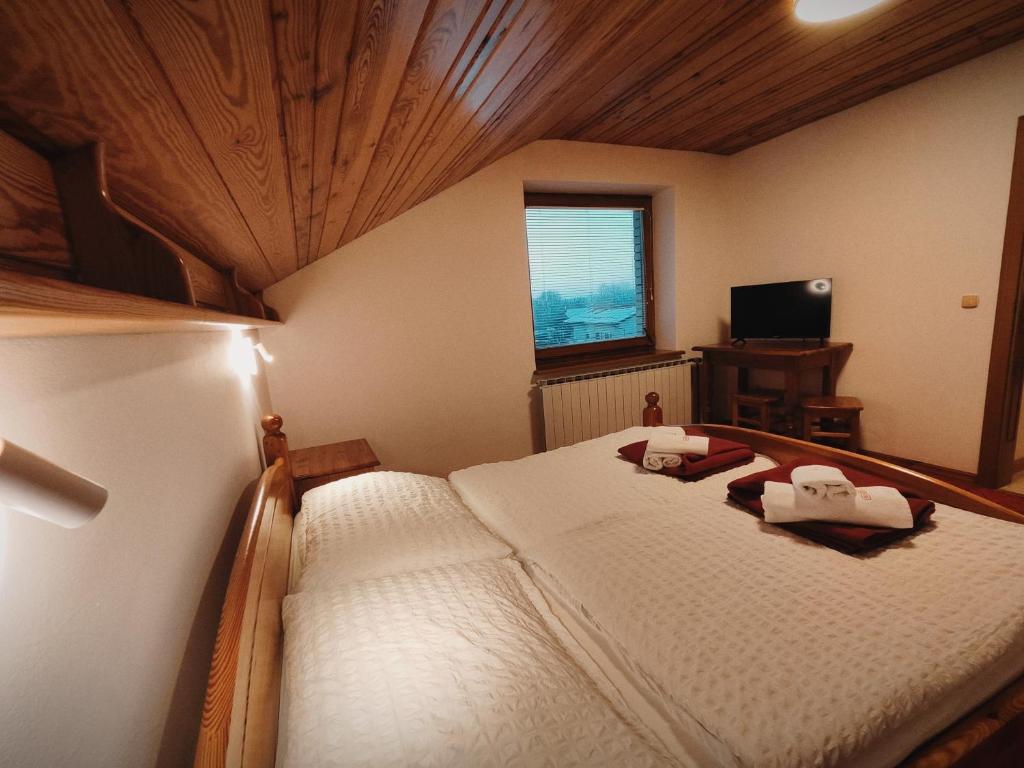 摩拉瓦托普利采畔可儿旅馆的卧室配有一张白色大床和木制天花板