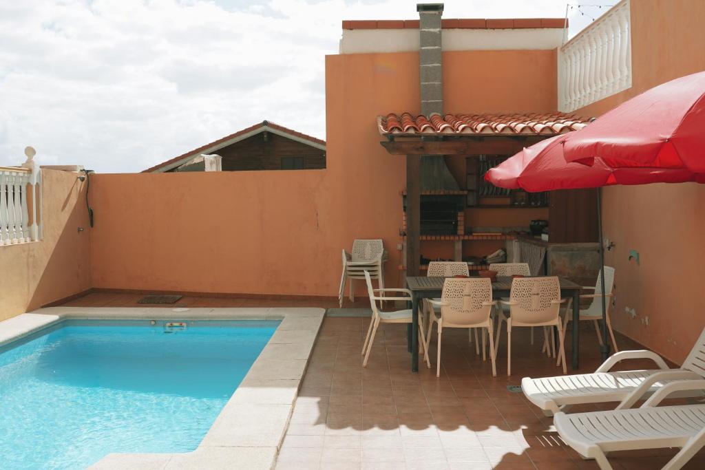 IguesteCasa Morales的一个带椅子和桌子的游泳池以及一把遮阳伞