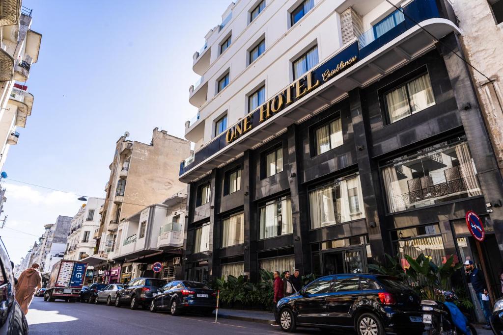 卡萨布兰卡One Hotel Casablanca的街道上的建筑物,前面有车辆停放