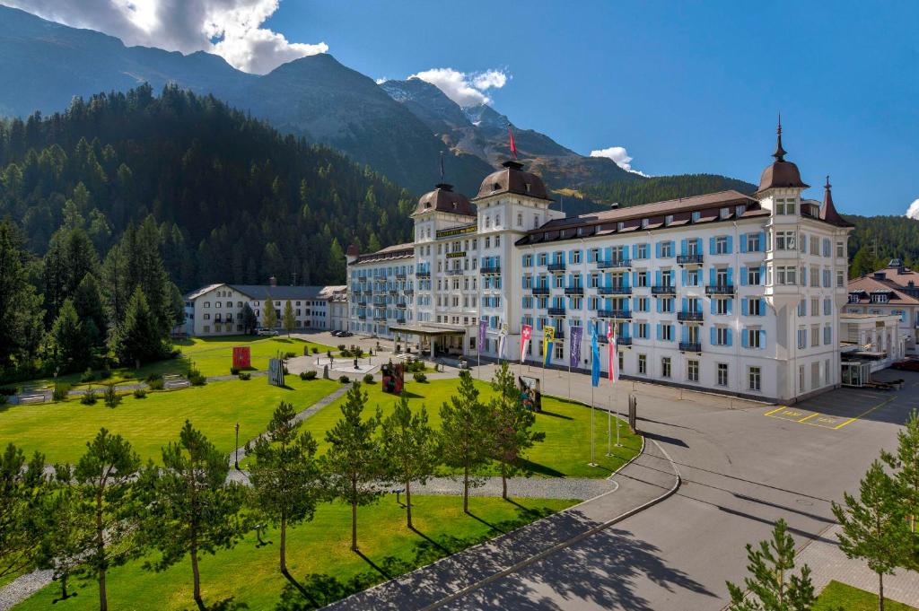 圣莫里茨Grand Hotel des Bains Kempinski的一座白色的大建筑,背景是群山