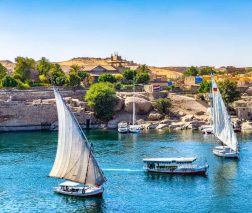 阿斯旺جوله بفلوكه في نهر النيل的一条城市背景河流上的三艘帆船