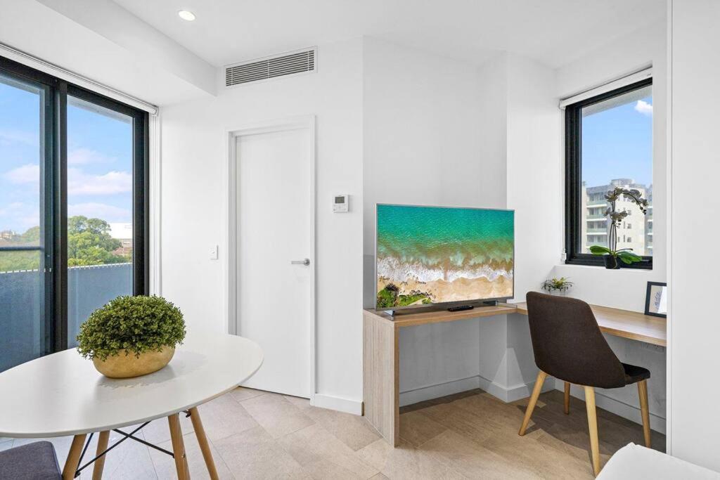 悉尼Lovely Studio apartments in Strathfield CBD的白色的客厅配有桌子和电视。