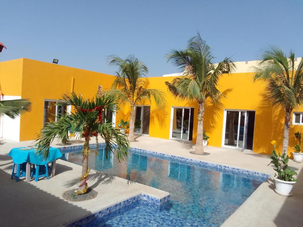 尼亚加Hôtel Colibri的一座黄色的建筑,设有游泳池和棕榈树