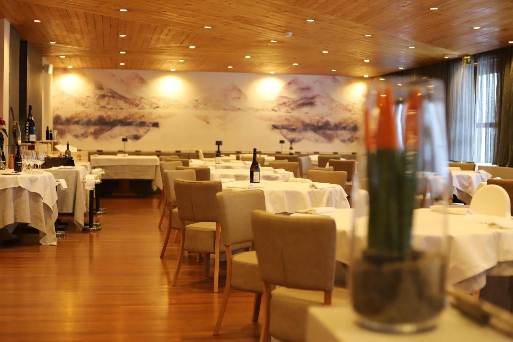 摩德纳迪-坎皮格里奥格力弗恩斯泰尔酒店的餐厅设有白色的桌椅和大屏幕