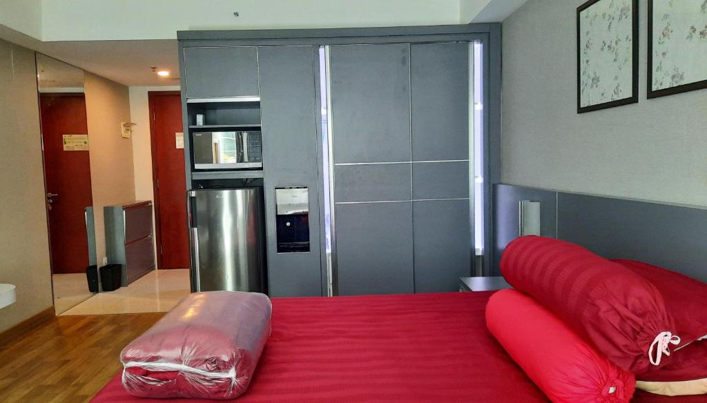 斯勒曼Apartment Mataram City Yogyakarta的一间卧室配有红色的床和红色枕头