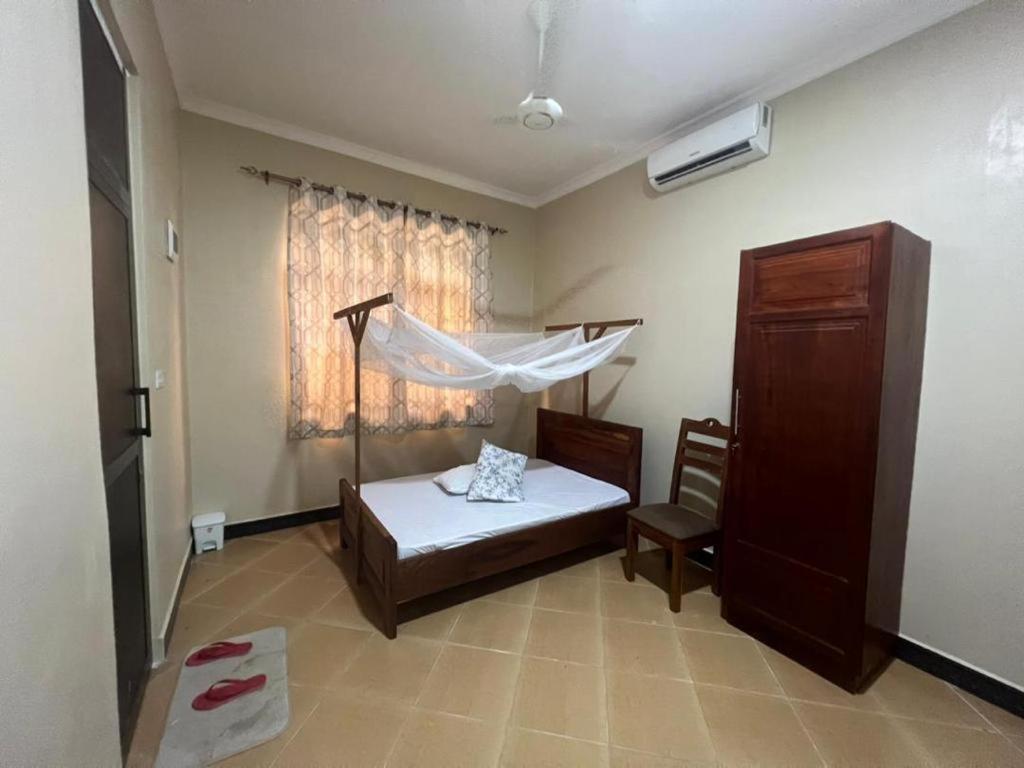 达累斯萨拉姆J & S LUGALLA HOUSE的一间卧室配有一张床,窗户配有蚊帐
