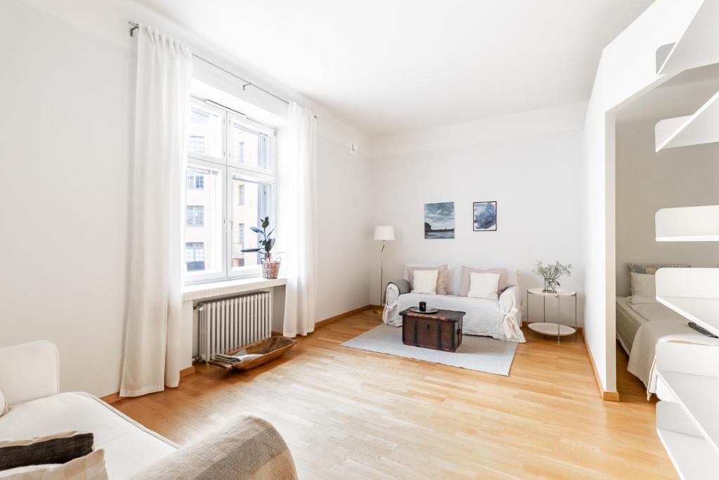 赫尔辛基Cozy, spacious and calm city home - top location的客厅配有白色家具和大窗户