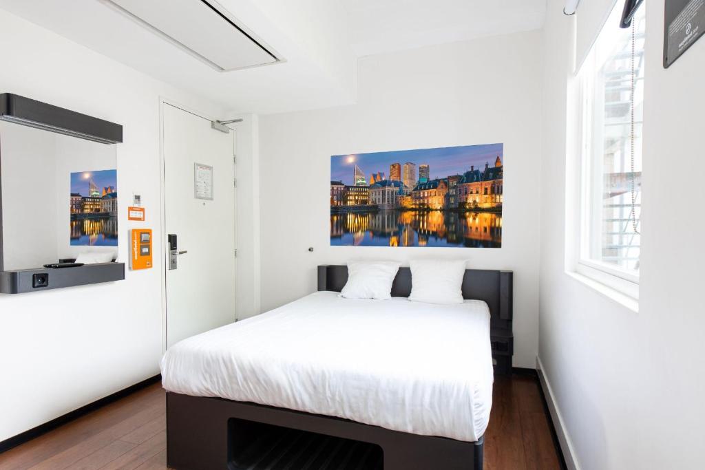 海牙easyHotel The Hague City Centre的卧室配有一张床,墙上挂有绘画作品