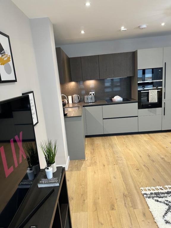 伦敦Richardson Deluxe Apartments (2-Bed)的厨房铺有木地板,配有白色橱柜。