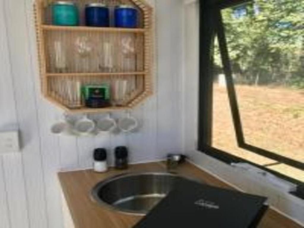 马莱尼White Jacaranda Tiny House的一个带水槽和窗户的小厨房