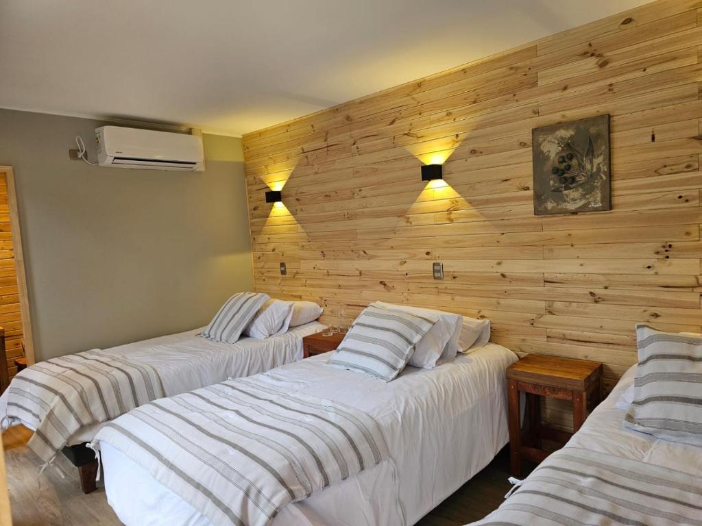 安东尼奥港Hotel Bacaris的带木墙的客房内的三张床