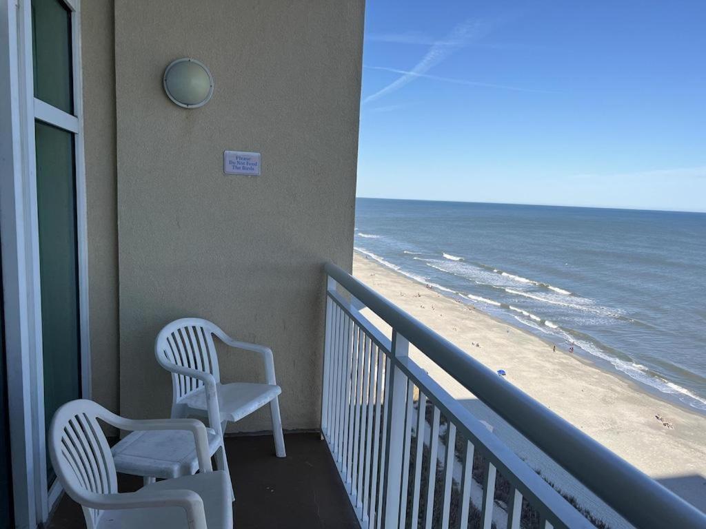 默特尔比奇2501 S Ocean Blvd, 1205 - Ocean Front Sleeps 6的两把椅子坐在俯瞰海滩的阳台上