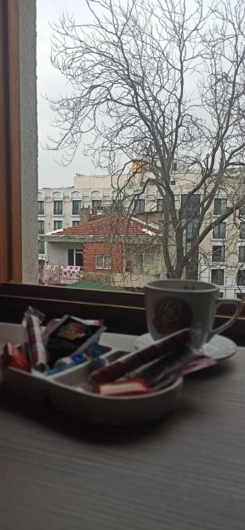 伊斯坦布尔NarPera Taksim Boutique Hotel的窗边桌子上带杯的盘子