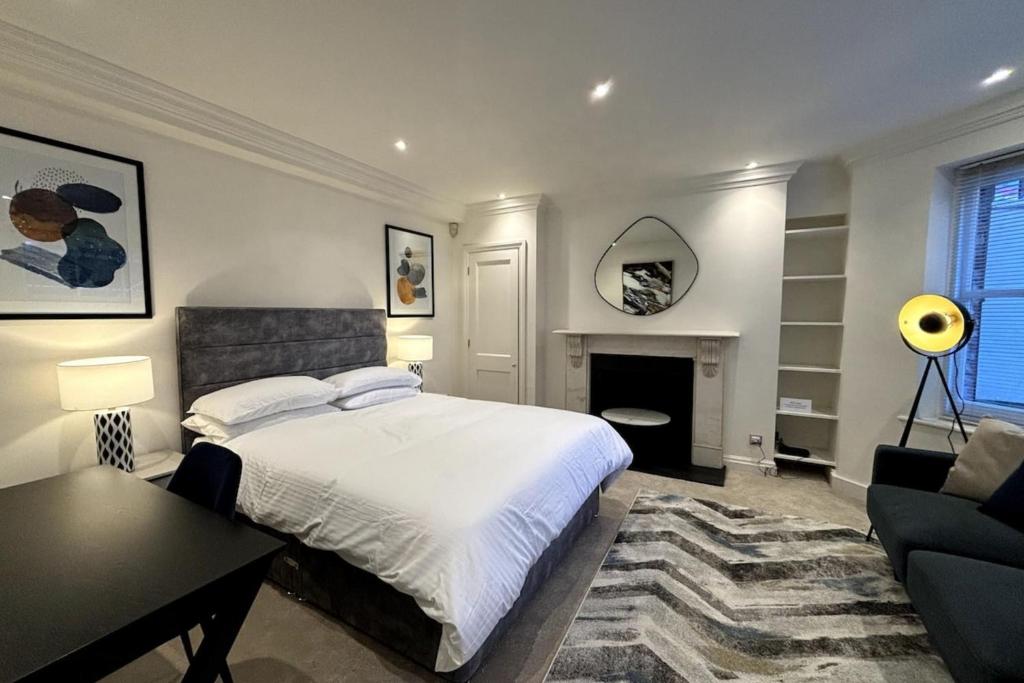 伦敦Chic Studio Flat 8 Mins to Harrods Knightsbridge的一间卧室配有一张床、一张桌子和一个壁炉