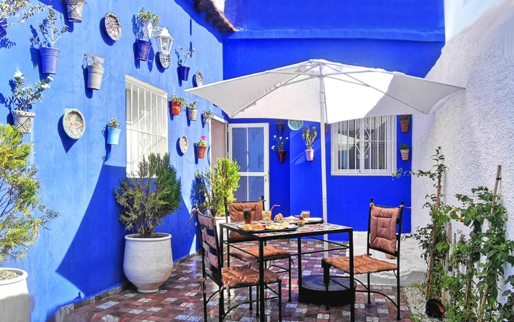 舍夫沙万Aparthotel Dar Nowara Chaouen的蓝墙前带雨伞的桌子