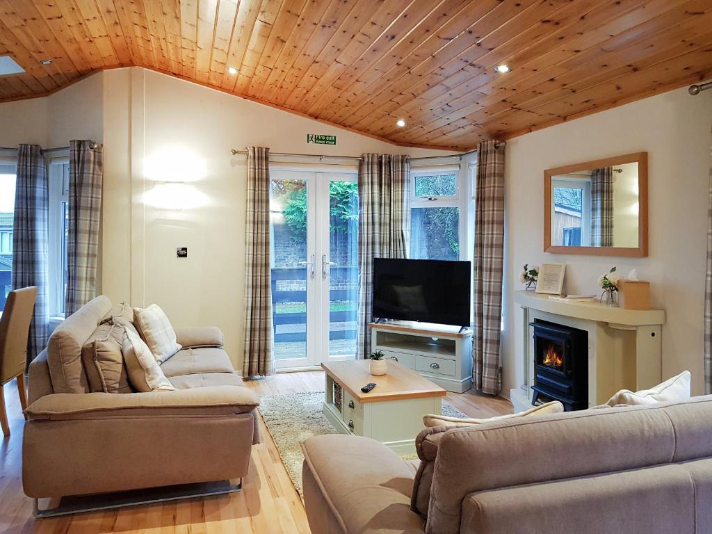 巴洛赫Kingfisher Lodge - Uk46046的带沙发、电视和壁炉的客厅