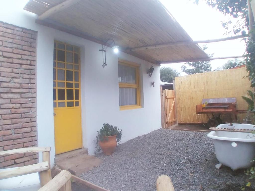San RoqueCASITA PINTORESCA EN LAS SIERRAS Y LAGO的白色的房子,有黄色的门和栅栏