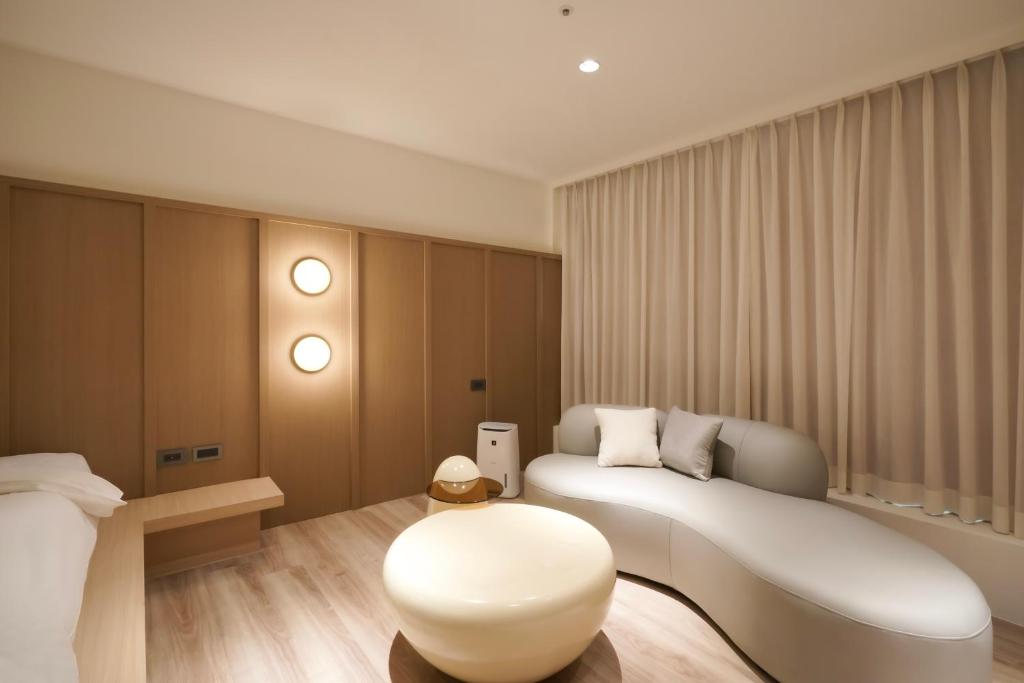 台南Hope Hotel Tainan的卧室配有白色沙发和凳子