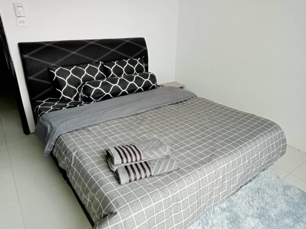 斯里曼绒Spacious+Minimal+Manjung City Centre的一张带黑色灰色棉被和枕头的床