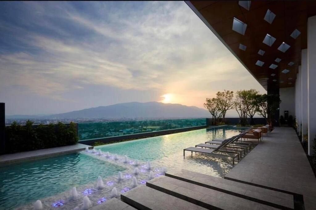 清迈Escent condo Chiangmai F17的一个带椅子的游泳池,享有日落美景