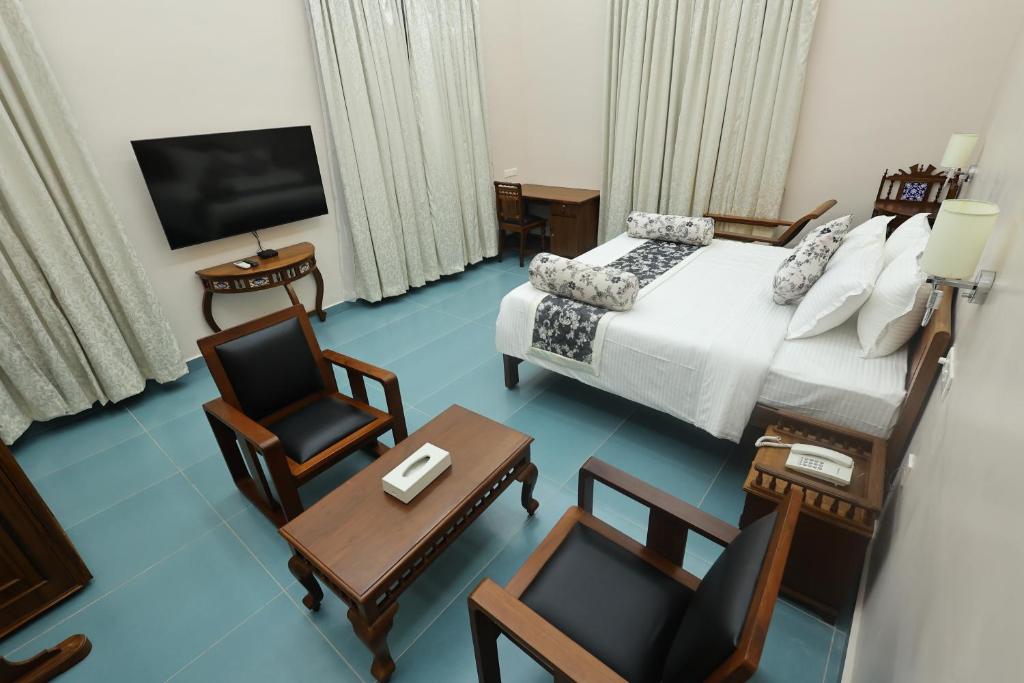 蓬蒂切里Le Colonial Suites的酒店客房配有床、椅子和电视。