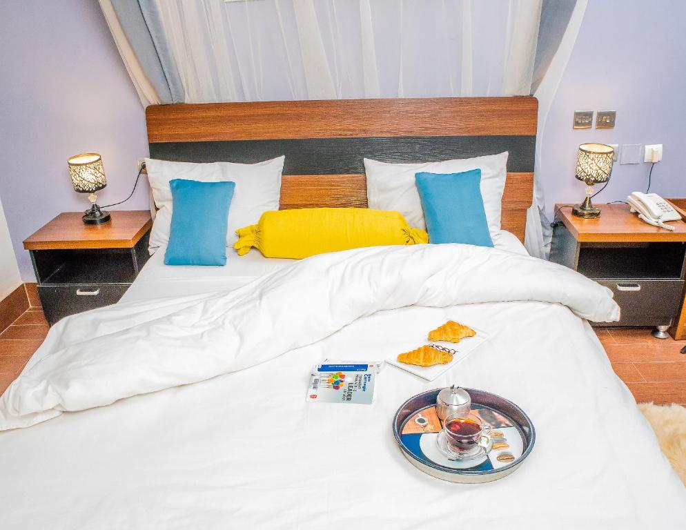 布琼布拉Hotel Hibiscus的一张白色的床,上面放着一盘食物