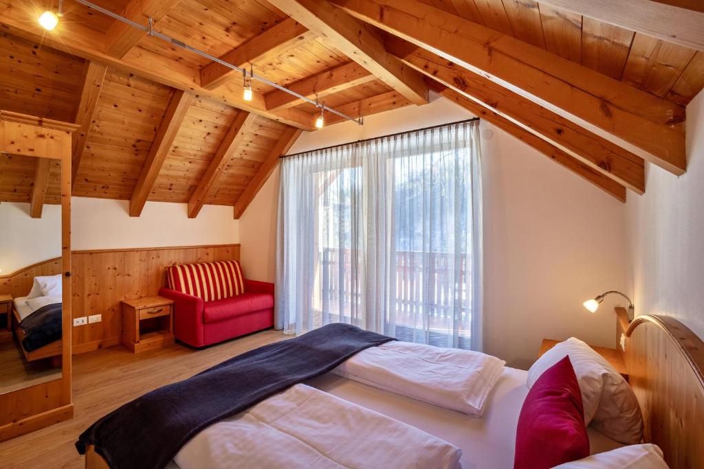 瓦尔道拉Apartments Perfila Ferienchalet的一间卧室配有一张床和一张红色椅子