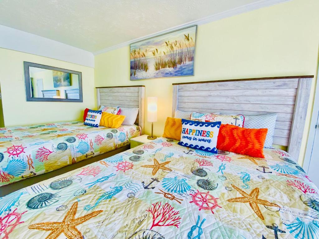 默特尔比奇Ocean Reef- Unique Oceanfront Condo-Free parking - Amazing pools的一间卧室配有两张带色彩缤纷枕头的床