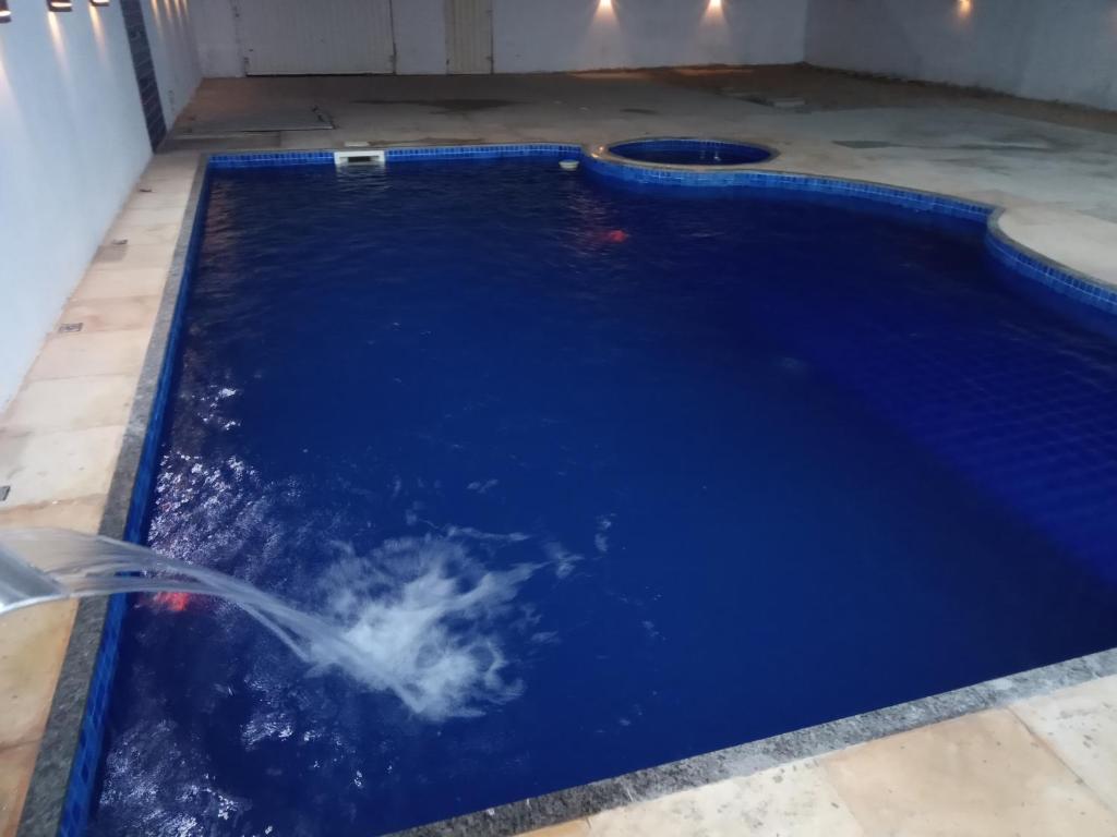 卡诺格布拉达Casa com Piscina, hidromassagem e churrasqueira.的蓝色海水和软管的游泳池