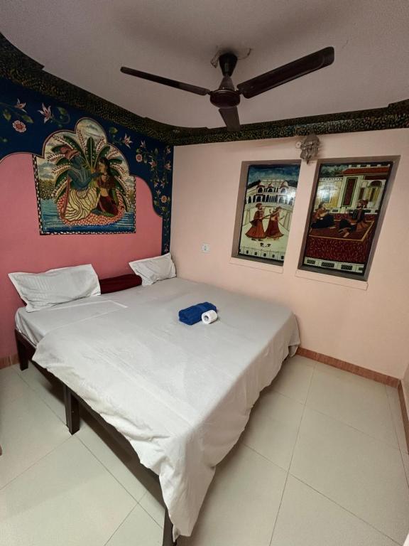 焦特布尔Shyam Hostel的墙上挂有绘画的客房内的两张床