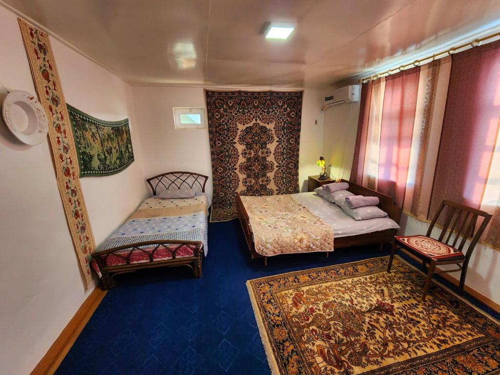 布哈拉Zafar Family Guesthouse的一间卧室配有两张床和两把椅子,铺有地毯。