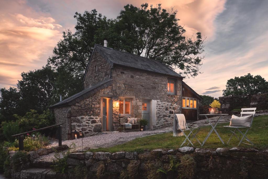 牛顿阿伯特Hawthorn Cottage at Collihole的石头小屋前面设有桌椅