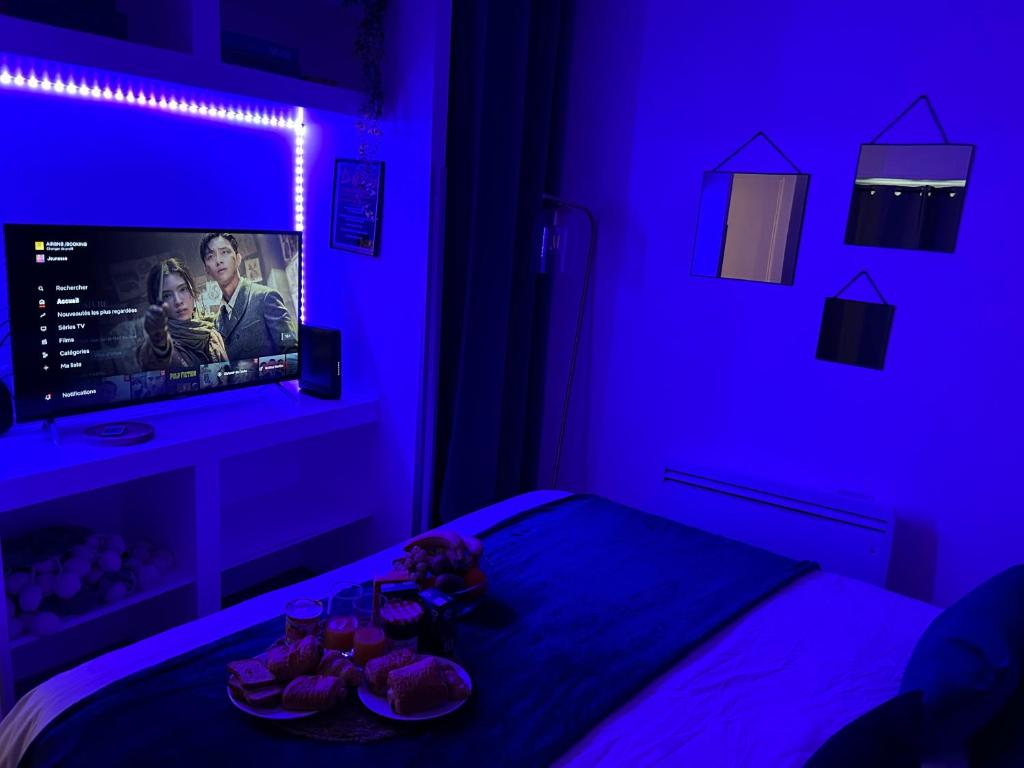 迈松拉菲特Appart' Studio cooconing - Champs Elysées - JO 2024的一间卧室配有紫色灯和一张带电视的床。