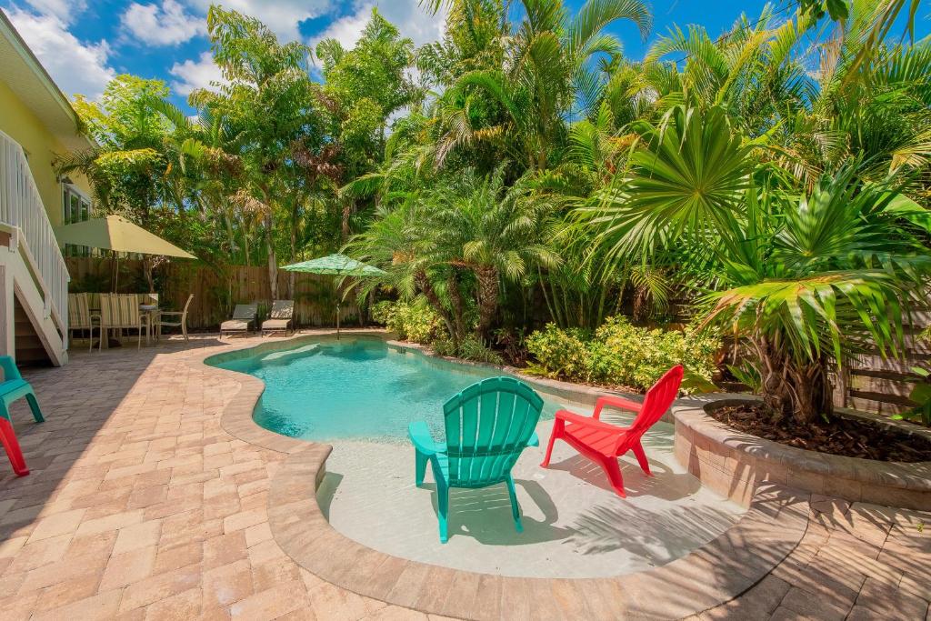 霍姆斯海滩Hawaiian Tide的一个带椅子和棕榈树的游泳池的庭院