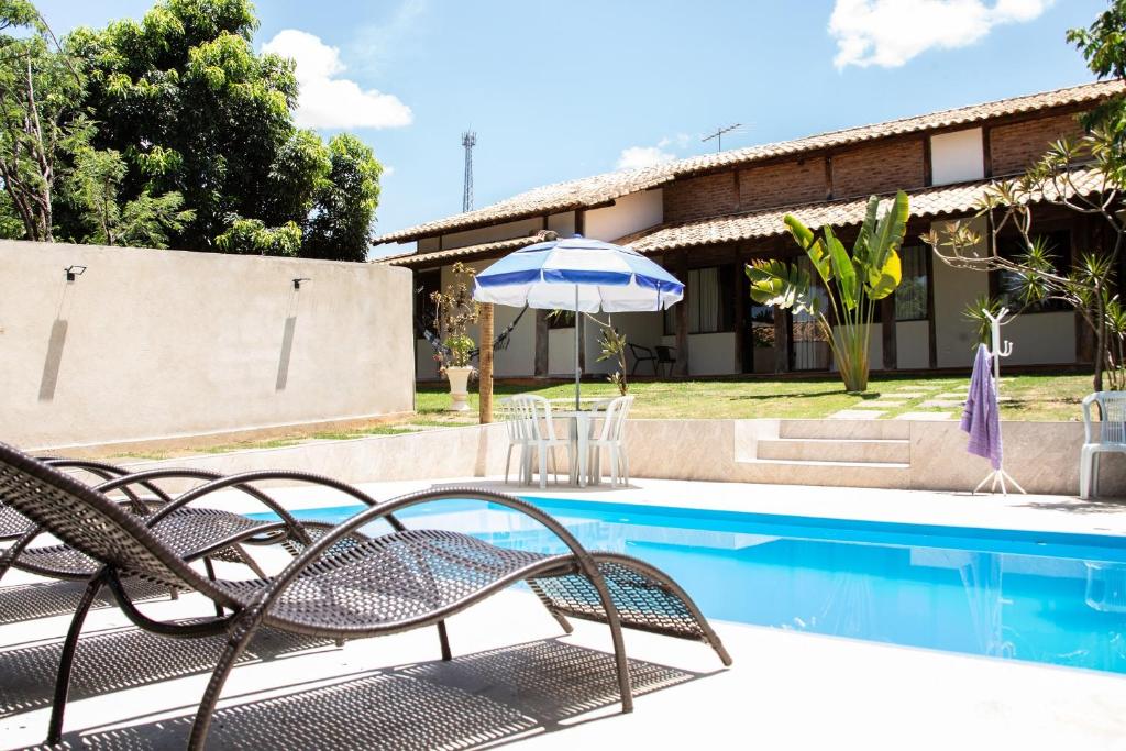 圣湖镇Casa das Pedras的房屋旁的游泳池配有椅子和遮阳伞