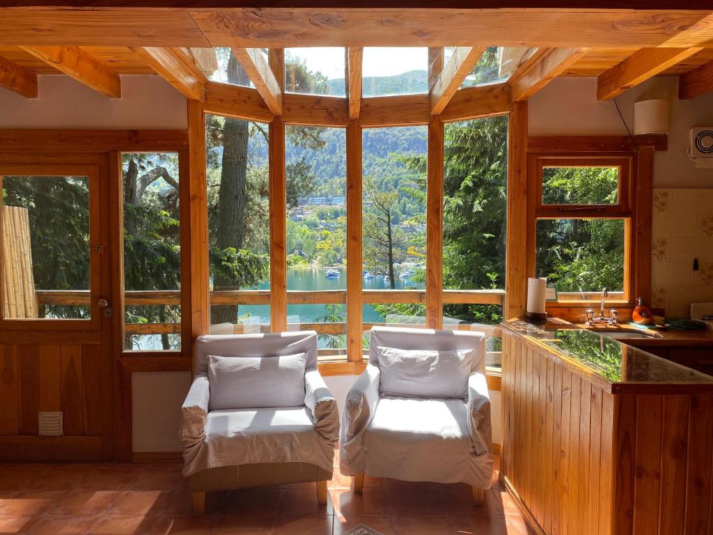 拉安戈斯图拉镇BOG Le Pommier - Cabañas con vista al lago y piscina climatizada的客厅配有两把椅子和大窗户