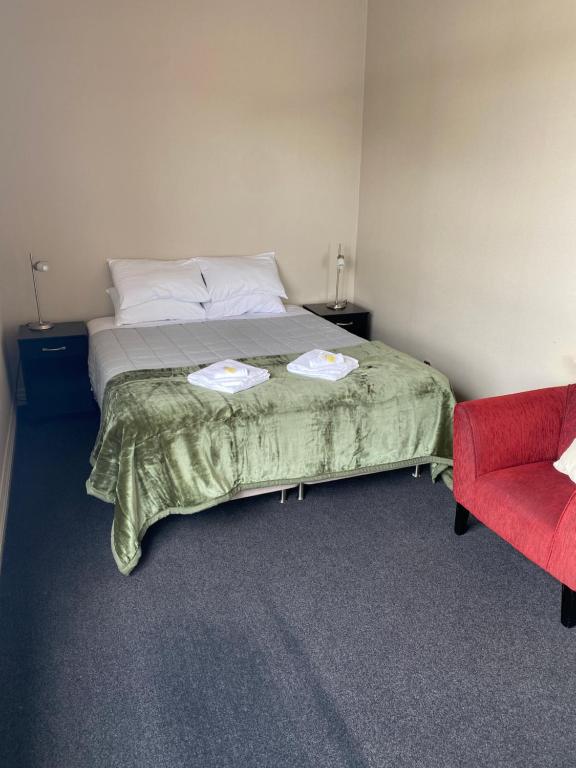 KapongaKaponga Hotel的一间卧室配有一张床和一张红色椅子