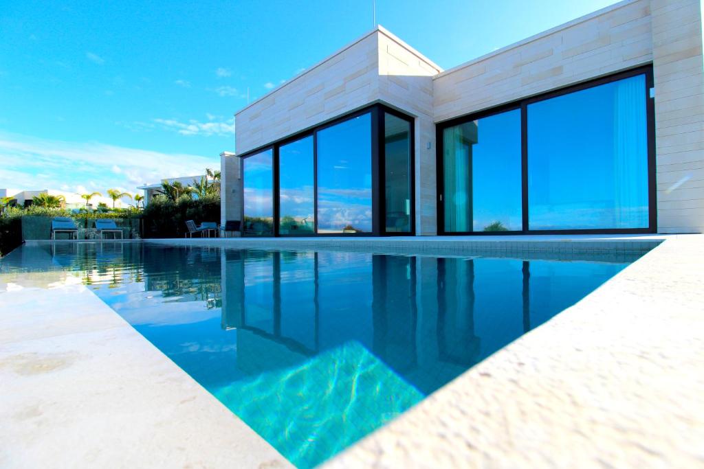 都拉斯Deluxe Villa Jante Infinity Pool的一座带玻璃窗户的游泳池的房子