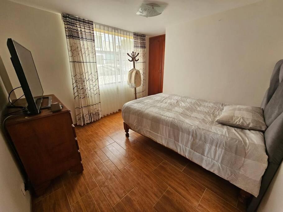 阿雷基帕Casa familiar en Arequipa的一间卧室配有一张床和一台电视,铺有木地板